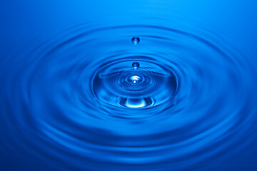 Group of water droplets fall and bounce on a water surface