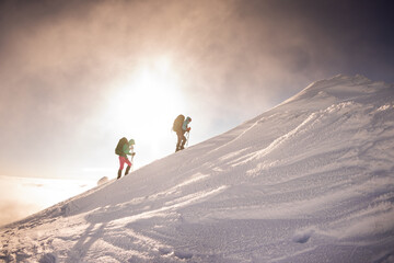 two girls with a backpack and snowshoes walk in the snow during a snow storm.