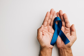 In November, a blue ribbon, symbolizing men's health and prostate cancer awareness, is held in...