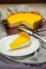 Fresh Lemon Cheesecake slice with fork and knife served in plate isolated on napkin top view cafe bake food
