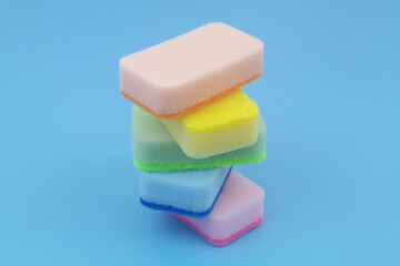 Stack of colorful sponges on blue background. Copy space for text.