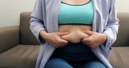 A woman shows an inflated thick belly, the concept of excess weight and weight loss