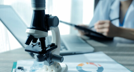 Young scientists conducting research investigations in a medical laboratory, a researcher in the foreground is using a microscope