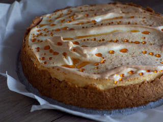 Classical cheesecake with meringue on white paper background. Homemade cheesecake with caramel drops. Cooking desserts and cakes. Confectionery. Top view.