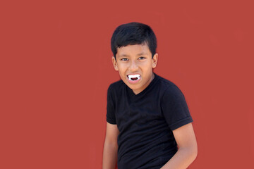 9-year-old dark-skinned Latino boy wearing vampire costume teeth to play and trick-or-treat on Halloween