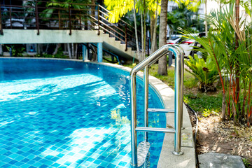 Ladder stainless handrails for descent into swimming pool. Swimming pool with handrail . Ladder of a swimming pool. Horizontal shot. stairs swimming pool. Stainless steel ladder