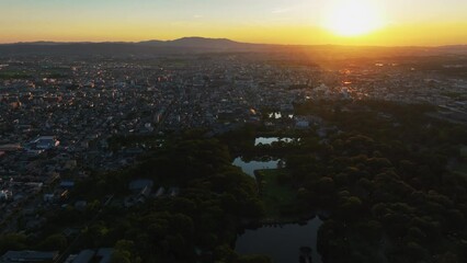 Drone shot tracking over the Nara park with sunlit city background, sundown in Japan