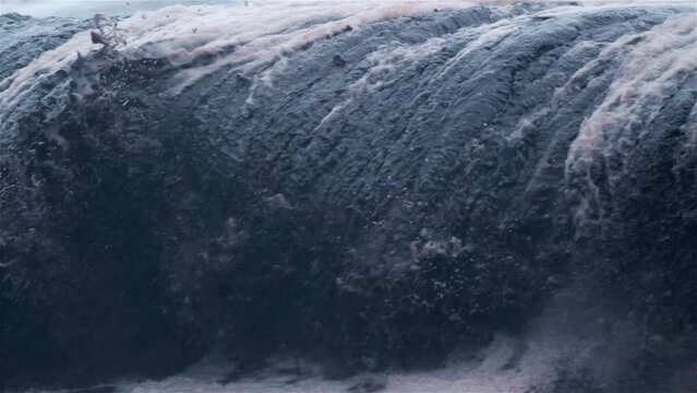 Muddy black wave crashes as debris floats in the water