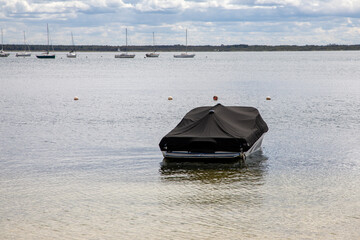 boat with grey protective tarpaulin cover on the lake water