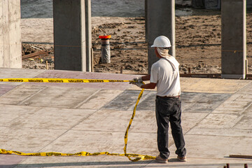 Construction worker placing caution tape at a construction site