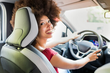 Cheerful black woman driving car