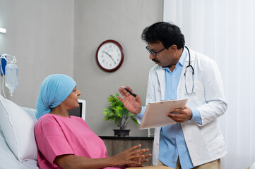 Indian Doctor Noting or writing cancer patient condition by asking Patient - concept of medical...