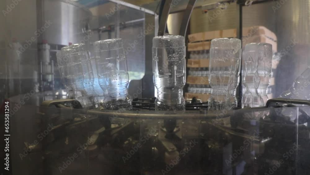 Poster automated bottle cleaning in a vinegar production facility. upside-down bottles on rotating machine.