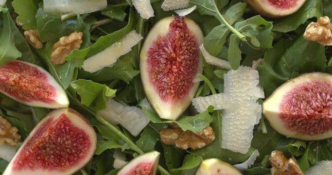 Close-up of arugula and fig salad with parmesan and walnuts. Table spin.