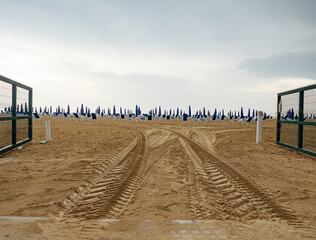 Wet sunbeds and umbrellas on the sea beach during rainy day. - 653587412