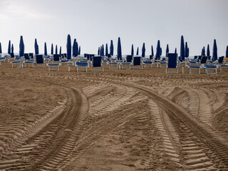 Wet sunbeds and umbrellas on the sea beach during rainy day. - 653587466