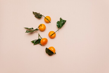 Orange tangerines with green leaves, scattered on a beige background. Clementine, mandarin. Top view. Flat lay