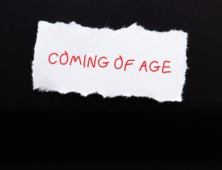 Torn paper on black copy space background with handwritten text COMING OF AGE -  time when person legally becomes an adult , matures emotionally, transition between childhood and adulthood