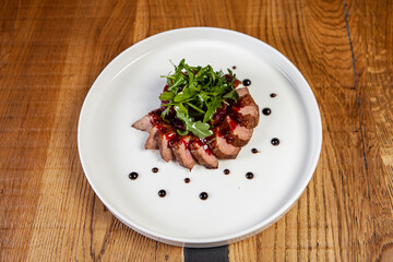 restaurant dish on a wooden table, steak, meat, arugula, sauce