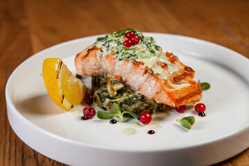 restaurant dish on a wooden table, salmon steak, spinach