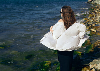 a beautiful woman in a summer dress walks on the beach near the raging sea