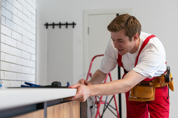 Gloved craftsman installs hob in kitchen. Household Appliance Installation Services Concept