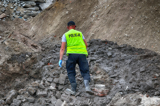 Policjant w ż&oacute;łtej kamizelce na miejscu wybuchu miny. 