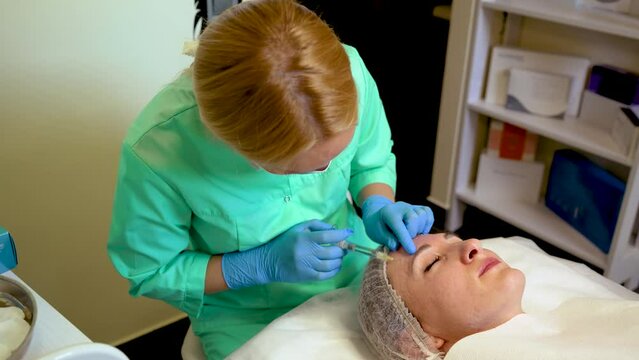 Skin care attentive cosmetologist provides botulinum therapy procedure to maintain health and beauty of woman's skin in cosmetic clinic. Cosmetology cabinet, medical procedures, skin rejuvenation