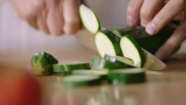 Chef in kiitchen cutting cucumber