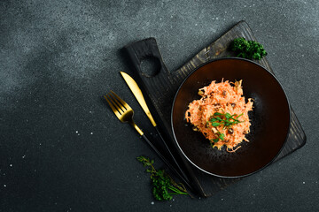 A plate of Homemade salad made of carrots, raisins, garlic and sour cream. On a black stone background. Free space for text.