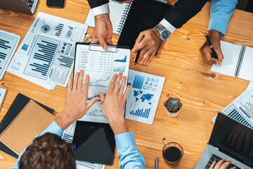 Top view diverse group of business analyst team analyzing financial data report paper on meeting table. Chart and graph dashboard by business intelligence analysis. Meticulous