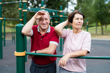 Elderly man and woman posing in open-air sports bars complex