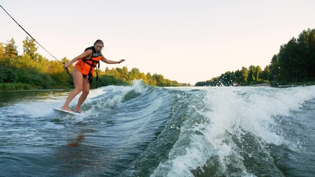 Water sports. River sports. Young woman water skiing on a lake. Waterboarding on the river. Woman in red life vest waterboarding.