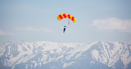 Skydiving. Flying parachutists against the background of the blue sky and mountains. Extreme sport and entertainment.
