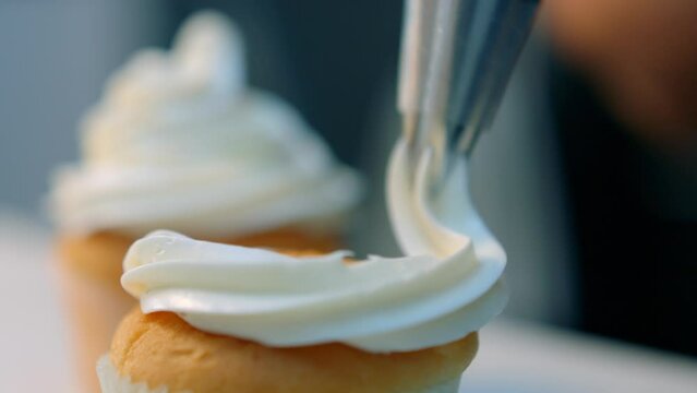 Frosting is piped onto a cupcake