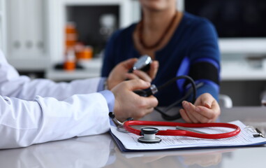 Close-up of doctor measuring pressure with tonometer to ill patient. Clipboard on table. Practitioner in medical gown and stethoscope. Health care and medicine concept