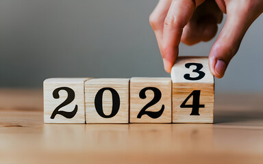 Cube turns from 2023 to 2024 on wooden table. Happy new year 2024 Merry Christmas and Happy New Year, blue background.2024 new year idea concept - obrazy, fototapety, plakaty