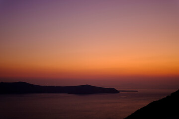 Orange and purple sunset sky in a coastal shore landscape in Santorini, Greece