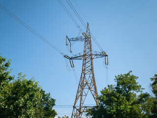 A high voltage power line mast rises above the trees against the sky