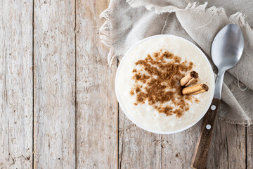Arroz con leche. Rice pudding with cinnamon in bowl on wooden table. Top view. Copy space