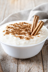Arroz con leche. Rice pudding with cinnamon in bowl on wooden table