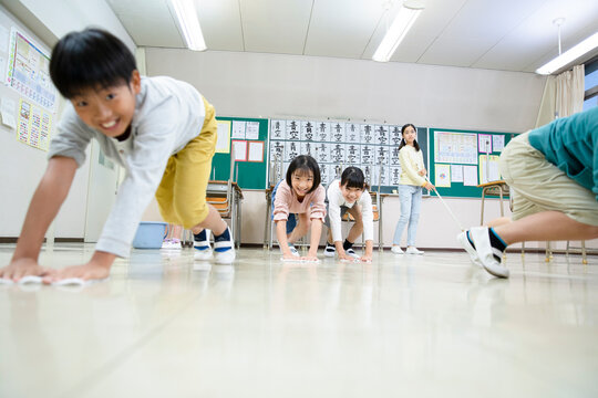 教室の床を雑巾がけする小学生たち