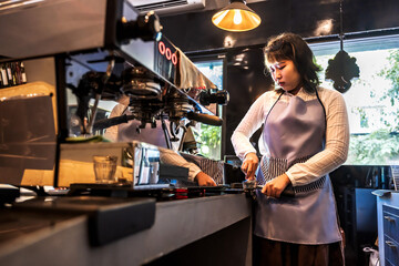 Fototapeta na wymiar Young coffee barista woman making espresso coffee in cafe