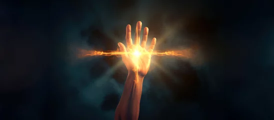 Gardinen Hand holding a glowing fire cross shaped on dark background © Faith Stock