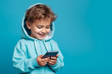 Portrait of cute little boy wearing blue hoodie isolated over blue background.