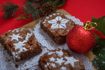 Chocolate brownies with icing sugar decorations together with Christmas decorations. Christmas background and dessert.