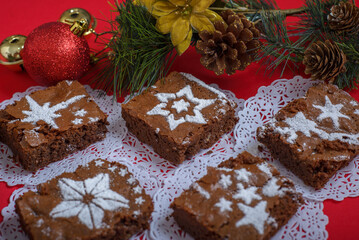 Chocolate brownies with icing sugar decorations together with Christmas decorations. Christmas background and dessert.