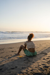 Fototapeta na wymiar Young hipster woman sitting on sand at the beach , enjoy sunset view, Bali , Indonesia