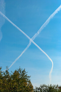 Condensation traces from two planes in the blue sky in the form of a cross