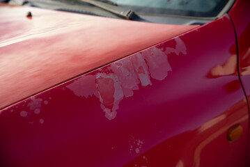 old peeling paint on the hood of a red car